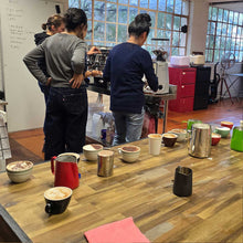 Load image into Gallery viewer, A group of students learning how to make coffee in the beginners barista training course