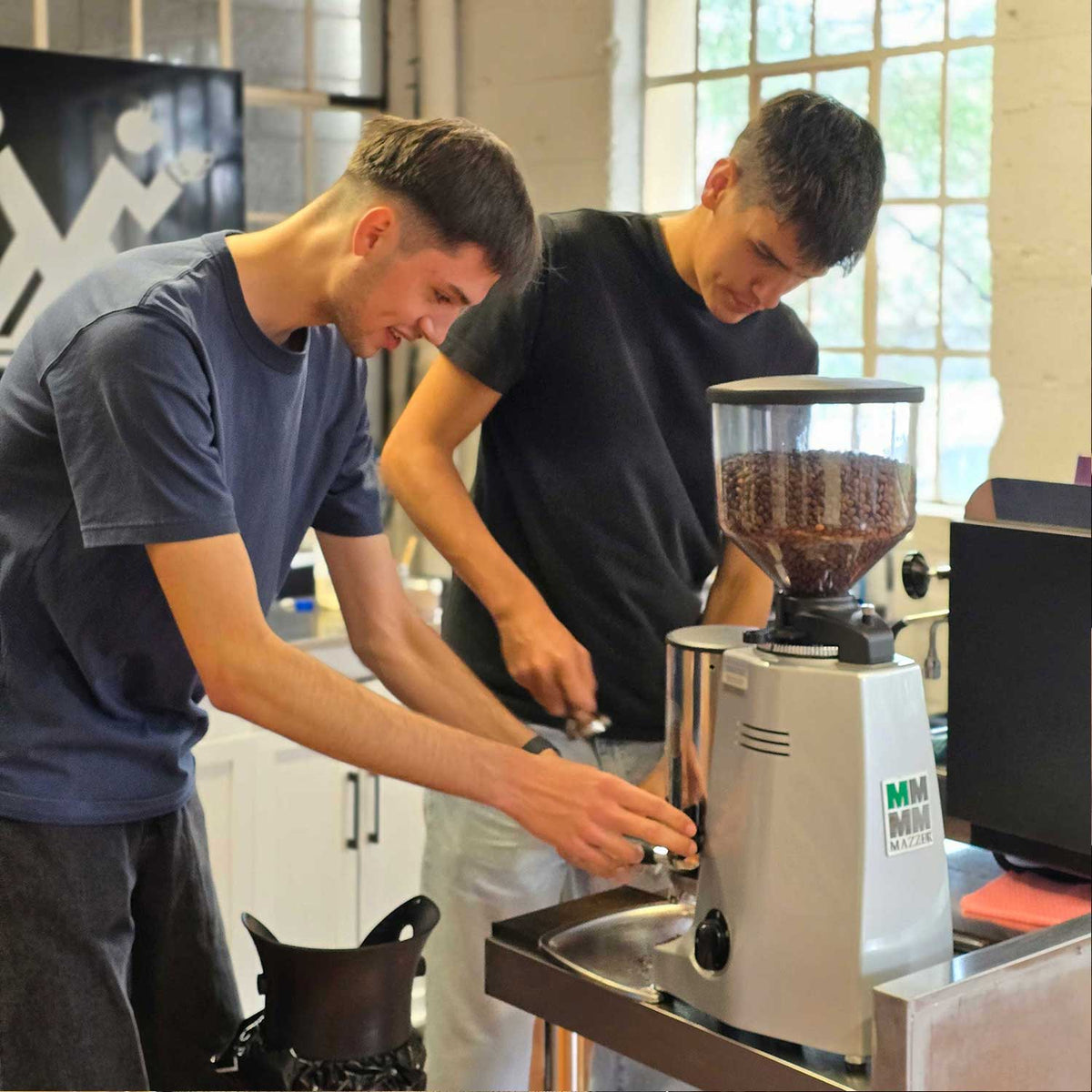 two men learning how to use a coffee grinder in our beginners barista training class