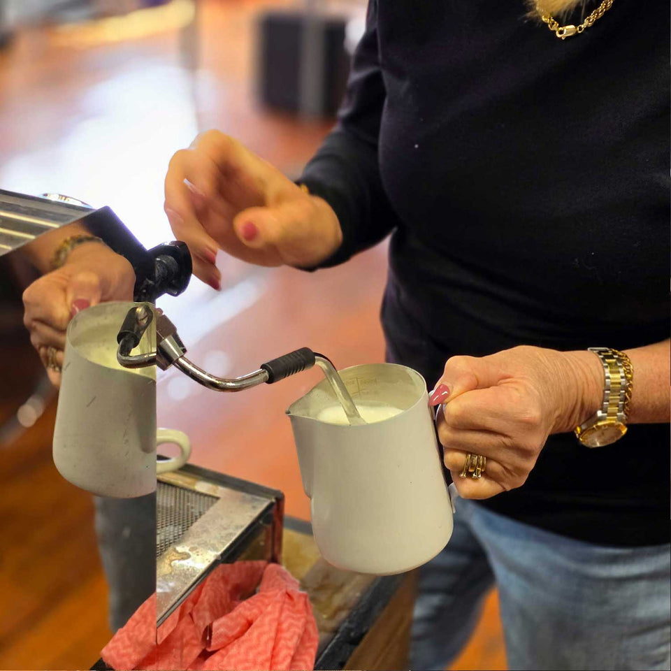 person learning how to froth milk on a home espresso machine